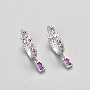 Detailed macro shot of silver hoop earrings with star carving and pink zircon pendants