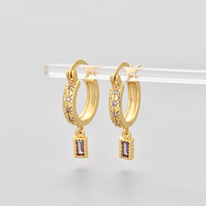 Detail of 18K gold hoop earrings with star engravings and a purple zircon rectangle charm