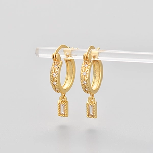 Detail of gold huggie earrings with star engraving and rectangular cubic zirconia pendant