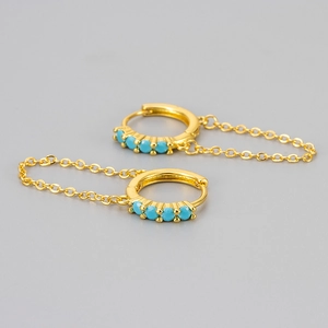 Detailed close-up of golden chain hoop earrings with inlaid turquoise stones