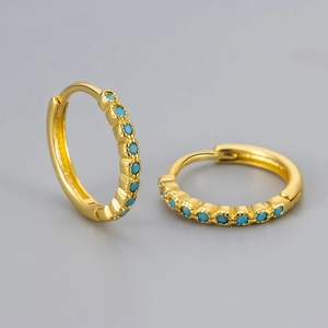 Close-up of gold huggie earrings with turquoise blue stones in micro-pave setting