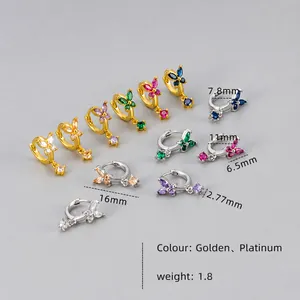 Detailed macro view showing gold and silver butterfly earrings with colorful zircon stones
