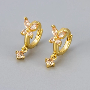 Close-up of gold butterfly earrings with champagne zircon stones on grey background