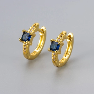 Close-up of gold-plated silver huggie earrings with square blue zircon and 925 stamp
