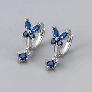 Detail of silver butterfly earrings featuring deep blue marquise stones and round drop pendants
