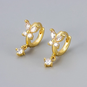 Close-up of golden butterfly earrings with sparkling zircon wings and crystal drop charms