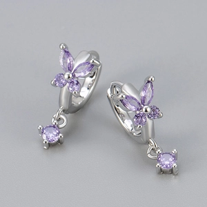 Detailed macro of silver butterfly earrings with purple zircon stones and drop design