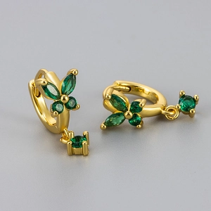 Detailed close-up of gold butterfly earrings with sparkling emerald green zircon gemstones