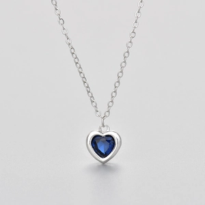 Detail van de zilveren hartketting met donkerblauwe edelsteen en ronde schakelketting