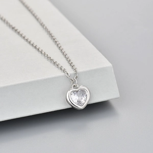 Elegante zilveren hartjesketting met glanzende zirkoonsteen op een moderne grijze display