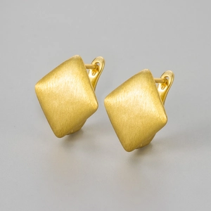 Macro shot of geometric square earrings featuring premium brushed gold metal texture