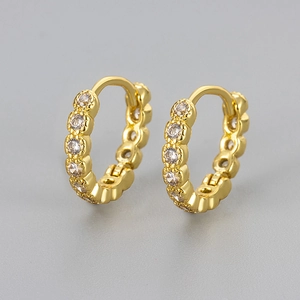 Dettaglio di orecchini huggie dorati con pavé di zirconi cubici tondi scintillanti