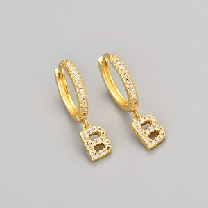 Detailed view of gold hoop earrings with sparkling zircon micro-pave and letter B pendant
