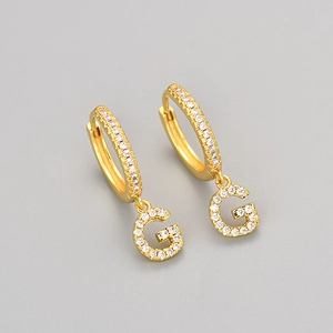 Detail view of gold earrings featuring a G letter pendant with micro-paved white zircons