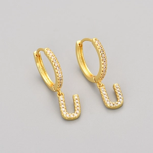 Macro shot of gold U-shaped drop earrings featuring shimmering micro-pave zircon stones