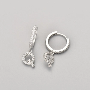 Detail view of silver earrings featuring micro-pave letter Q pendants with shiny cubic zirconia