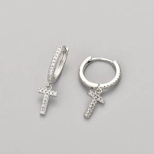 Macro detail of silver letter T drop earring with pave set crystals on a neutral background