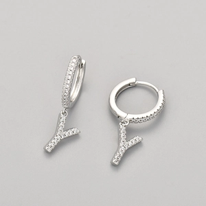 Detail of silver letter Y charm earrings with white zircons on a gray background