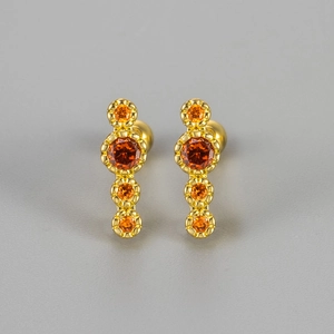 Detail of gold screw-back studs with four orange vertical zircons in claw setting