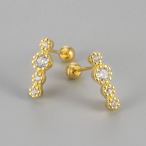 Macro shot of gold-plated screw back studs featuring four vertically aligned sparkling crystals