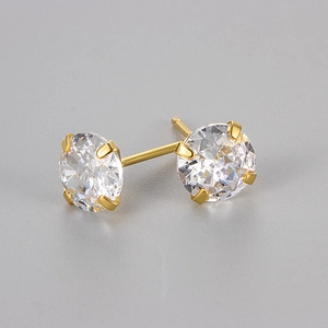 Détail de boucles d'oreilles dorées à quatre griffes avec zircons ronds brillants et nets