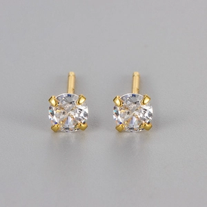 Détail macro de puces d'oreilles dorées avec serti à quatre griffes et zircon rond