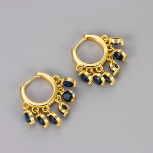 Dettaglio di orecchini a cerchio dorati con cinque pietre di zircone blu scuro pendenti
