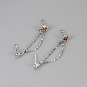 Detail view of silver chain earrings featuring clover garnet gems and a white zircon stud