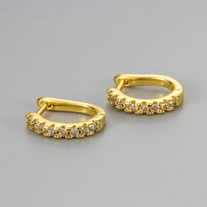 Macro shot of gold-plated D-shaped earrings featuring a row of sparkling white zircons