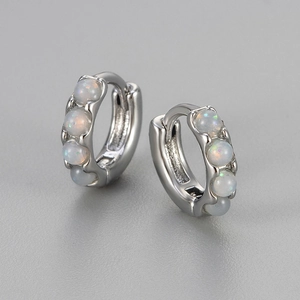 Macro shot of silver hoop earrings featuring four round inlaid opal gemstones