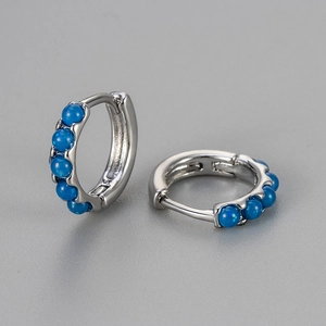 Detailed view of silver huggie earrings featuring five round blue opal stones with sparkles