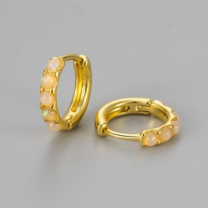 Detail of round opal earrings with sparkling crystals in a golden hoop design