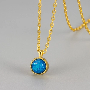 Elegante collana dorata con pendente in opale blu tondo e bordo metallico perlato