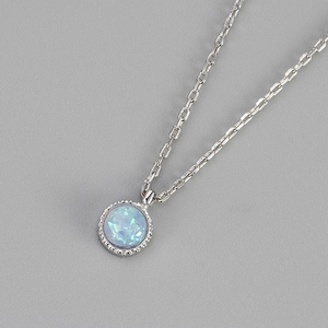 Dettaglio del pendente in opale blu rotondo con catena d'argento e riflessi iridescenti