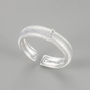 Macro detail of brushed silver ring featuring vertical stripes and three inset zircons