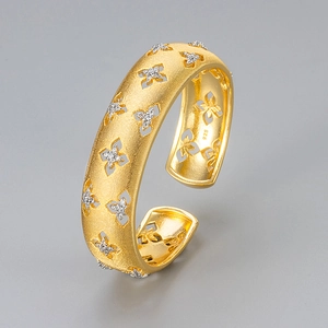 Brushed gold open bangle with hollow clover patterns and sparkling zircon stones