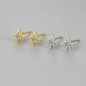 Macro view of dainty star stud earrings with central cubic zirconia in gold and silver