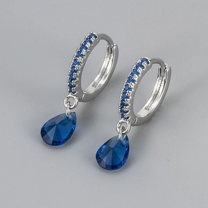 Macro shot of silver drop earrings featuring blue crystals and teardrop pendants