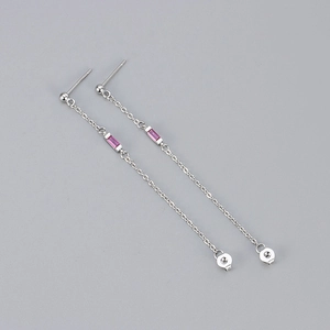 Detail of silver chain tassel earrings with pink cubic zirconia stones on grey background
