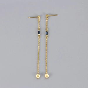 Detail of gold chain earrings featuring rectangular blue zircon stones and long tassels