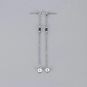 Detailed macro view of minimalist silver chain tassel earrings with black cubic zirconia