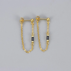 Detailed close-up of gold chain earrings featuring rectangular black cubic zirconia stones