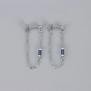 Macro shot of silver tassel chain earrings featuring a rectangular blue zircon stone