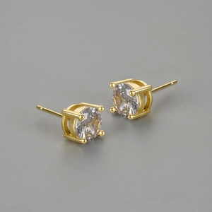Macro shot of gold-plated round cubic zirconia studs with a classic four-claw setting