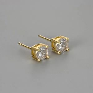 Classic gold four-prong stud earrings with round clear zircon on a grey background