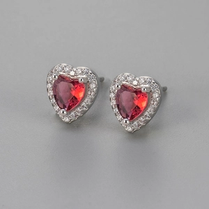 Detailed macro view of heart-shaped red zircon earrings with halo diamond setting