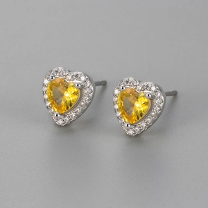 Detail of heart-shaped yellow zircon stud earrings with silver halo setting