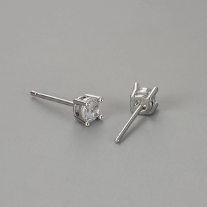 Macro close-up of classic four-prong round zircon stud earrings with silver metal finish