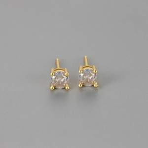 Macro shot of 4-prong round zircon stud earrings with classic gold plating finish