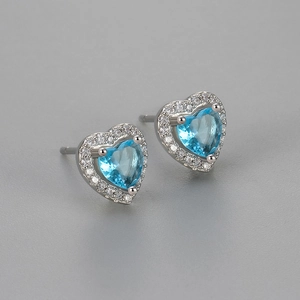 Macro shot of silver heart earrings with blue gemstone and pavé cubic zirconia
